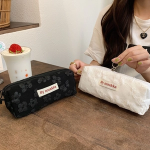 Detailed view of floral texture pencil cases in black and white with metal zippers