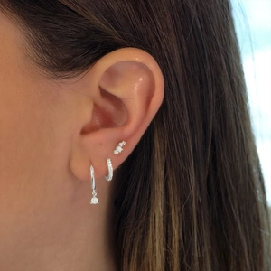 Macro shot of 925 sterling silver opal hoop earrings and studs worn on a model's ear