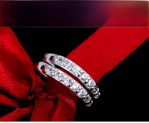 Macro shot of silver crystal hoop earrings displayed on red silk fabric background