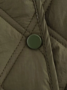 Detail einer olivgrünen gesteppten Jacke mit passendem Harz-Druckknopf-Verschluss