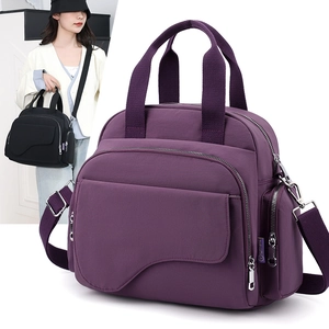 Detail of purple nylon handbag featuring multiple zipper pockets and adjustable strap