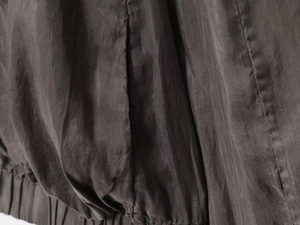 Detailed macro view of charcoal grey bomber jacket fabric with elastic hem finish