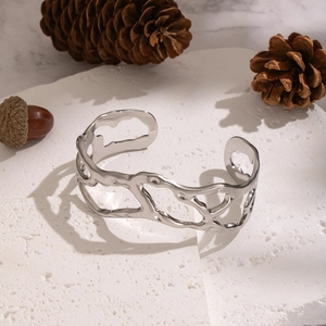 Detailed view of silver hollow irregular lava texture cuff bracelet on white stone