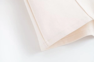 Detailed macro view of the double-needle stitching on off-white knitted fabric