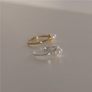 Detailed view of adjustable gold and silver pearl rings with minimalist design