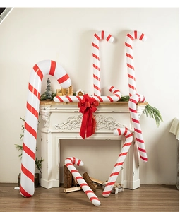 Multiple large red and white inflatable candy canes in a cozy Christmas fireplace setting