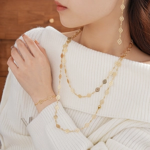 Detailed view of vintage gold hollow diamond clover necklace and bracelet set on a white sweater