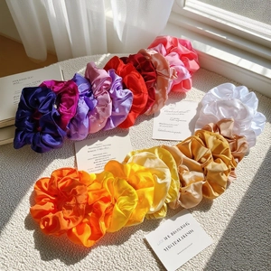 Macro detail of various colorful satin silk scrunchies with elegant glossy texture