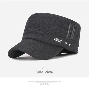 Detail view of dark grey wool flat top cap with metallic V-logo and side leather accents