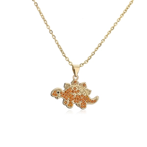 Detailed close-up of a golden dinosaur pendant encrusted with orange zircons and black eyes