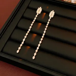 Elegant gold drop earrings with zircon tassel and wheat leaf design on black display