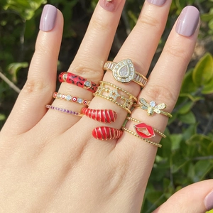 Détail d'un ensemble de bagues boho dorées avec lèvres en émail rouge et motifs abeilles