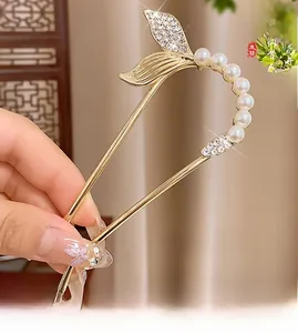 Détail d'une épingle à cheveux dorée en U avec motif queue de poisson et perles