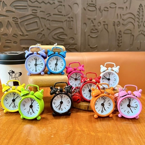 Colorful mini alarm clock keychains displayed on a miniature wooden chair