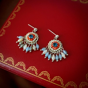 Detail of bohemian tassel earrings with blue gemstone and water-drop beads on red box