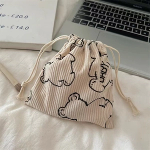 Close-up of a cream corduroy drawstring bag with a cute bear pattern and soft texture