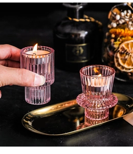 Detail of pink ribbed glass candle holders with warm tea light flame in a dark setting