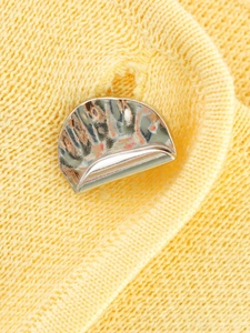 Détail d'un bouton métallique argenté sur un débardeur en maille jaune pour femme