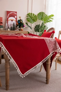 Macro shot of red Christmas deer tablecloth featuring white patterns and tassel fringe detail