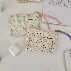 Floral makeup pouch with zipper closure on office desk next to laptop and mouse