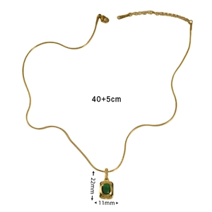 Close-up of gold snake chain necklace with emerald green gemstone pendant and sizing info