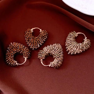Détail de boucles d'oreilles cœur en perles bronze et champagne sur tissu en soie