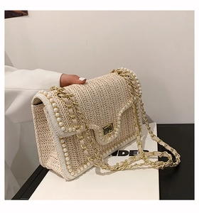 Close-up of cream woven bag with pearl trim details and gold chain strap