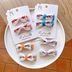Detailed close-up of embroidered floral bow hair clips with delicate white lace edges