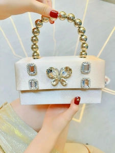 Macro detail of silk satin evening bag featuring crystal butterfly buckle and beaded handle