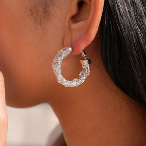Gros plan d'une boucle d'oreille géométrique argentée tissée portée par un mannequin