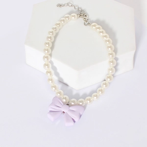Close-up of pearl pet necklace with a light purple resin bow and silver metal clasp