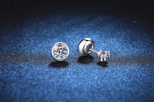 Macro shot of silver moissanite stud earring featuring a classic bezel setting and fire