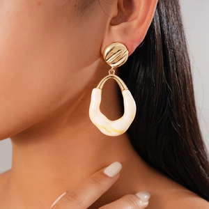 Close-up of geometric resin drop earring with textured gold top on female model