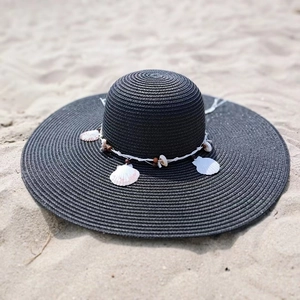 Detail of black woven straw hat featuring natural seashells and wooden beaded trim strap