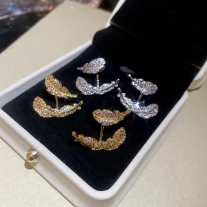 Elegant gold and silver leaf feather earrings with sparkling cubic zirconia on black velvet