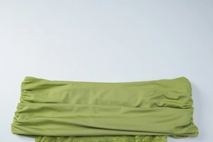 Detail of green lace stitching and pleated off-shoulder bodice texture on the dress