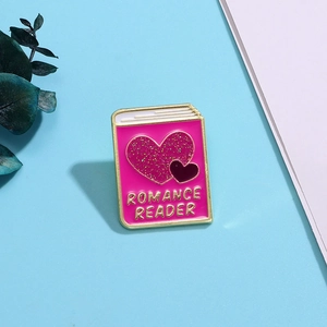 Detailed close-up of a pink heart-shaped book brooch with Romance Reader gold text