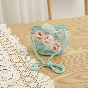 Détail d'un petit sac en paille vert menthe avec fleurs roses et nœud en tulle blanc