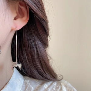 Detailed view of silver liquid metal tassel earrings worn by a model in lifestyle shot