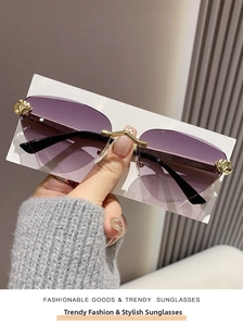 Close-up of rimless metal cheetah sunglasses with purple gradient lenses and gold accents