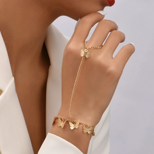 Close-up of a gold butterfly hand chain bracelet and ring set worn by a female model