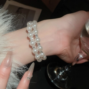 Close-up of double-layer pearl bracelet with rhinestones worn in an elegant social setting