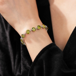 Detail view of a vintage silver bracelet with round green zircons worn on a female wrist