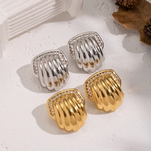 Textured gold and silver shell earrings with rhinestones on a white plaster background
