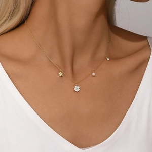 Close-up of gold star and pearl charms on S925 silver necklace worn by a model