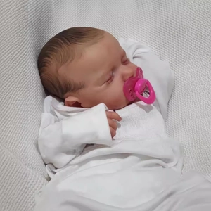 Realistic 19-inch reborn Loulou baby doll in white bodysuit with pink pacifier on knit blanket