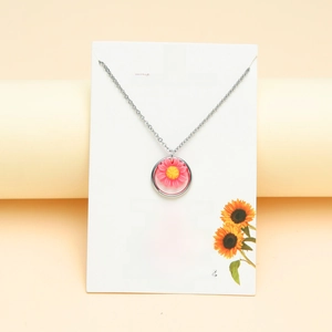 Detail of pink sunflower pendant necklace on inspiration card in professional setting