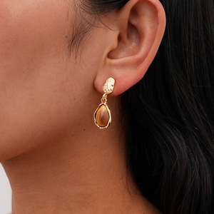 Detail of teardrop resin earring with textured gold finish on model for vintage look