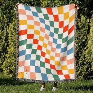 Detailed close-up of colorful checkered woven blanket with tassels on green grass