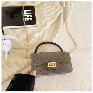 Detail of grey jelly crossbody bag featuring quilted PVC and black beaded handle